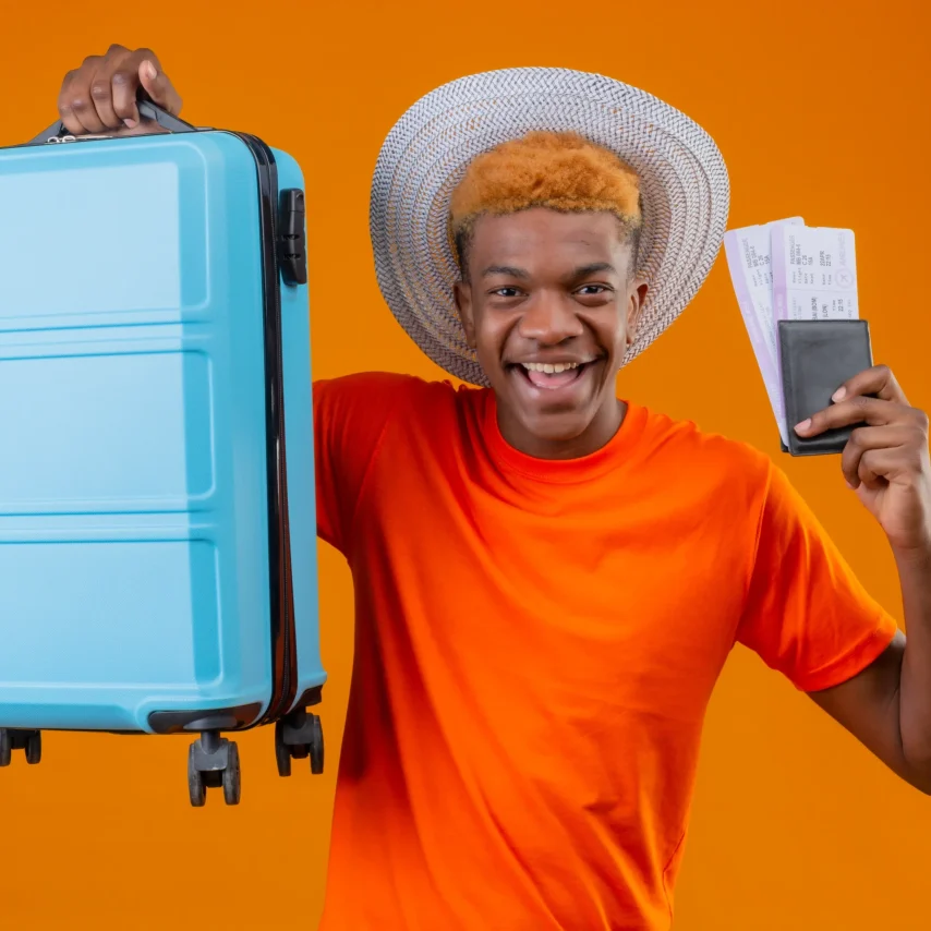 pleased-young-handsome-boy-wearing-orange-t-shirt-holding-travel-suitcase-airplane-tickets